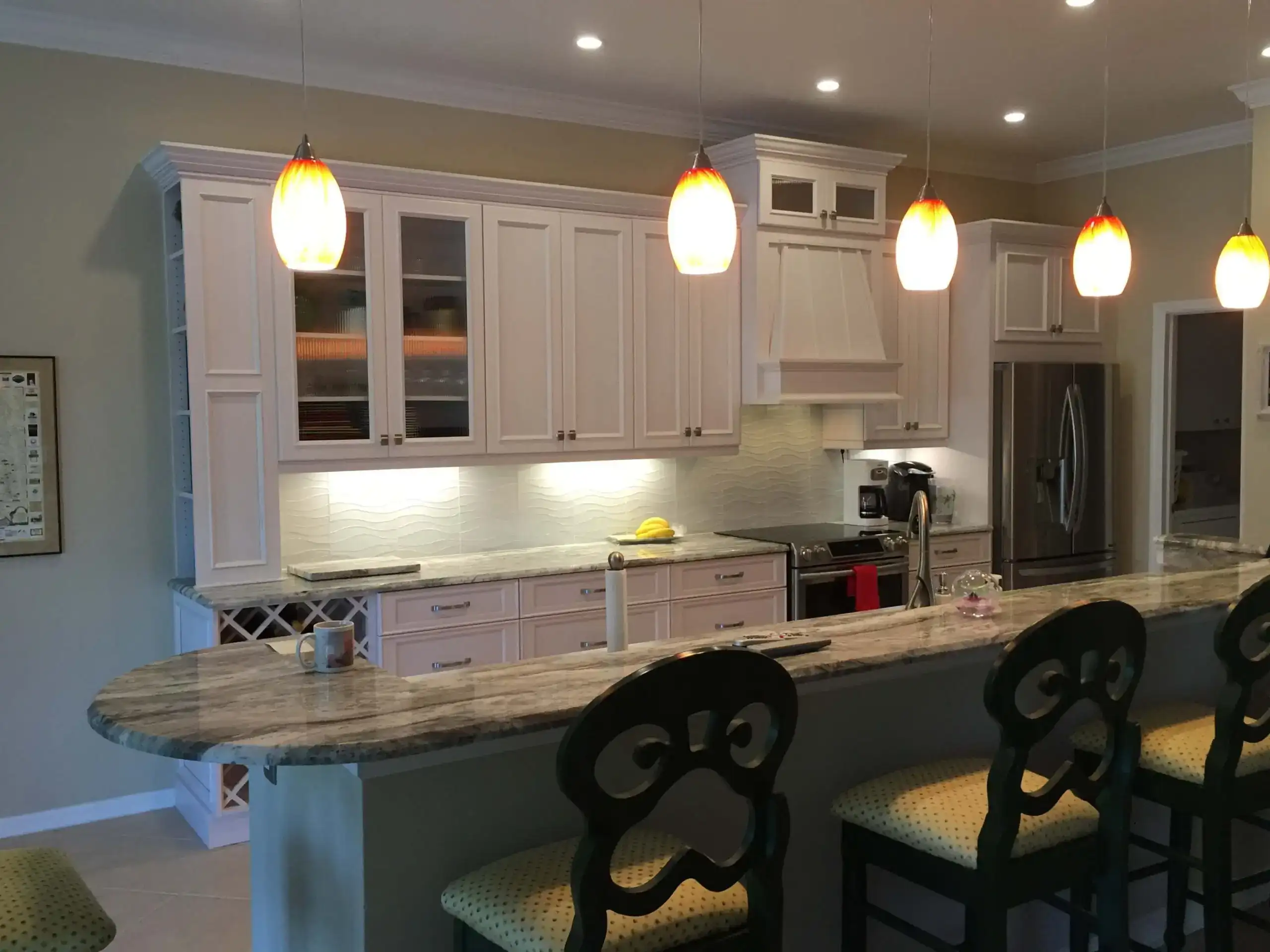 kitchen with natural stone counters, island, and custom white cabinetry